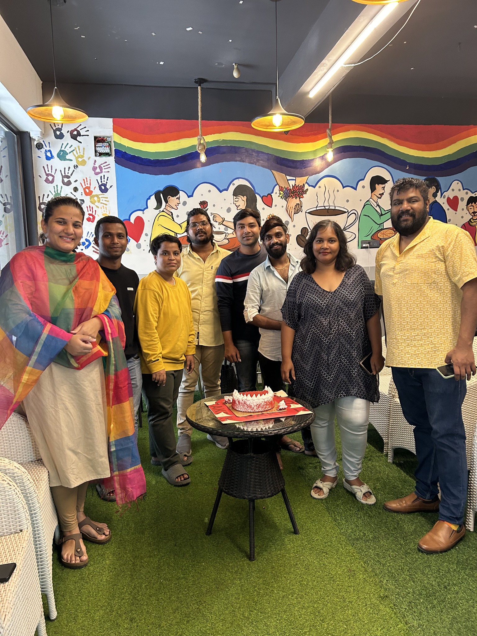 a group of people standing in a room with a cake