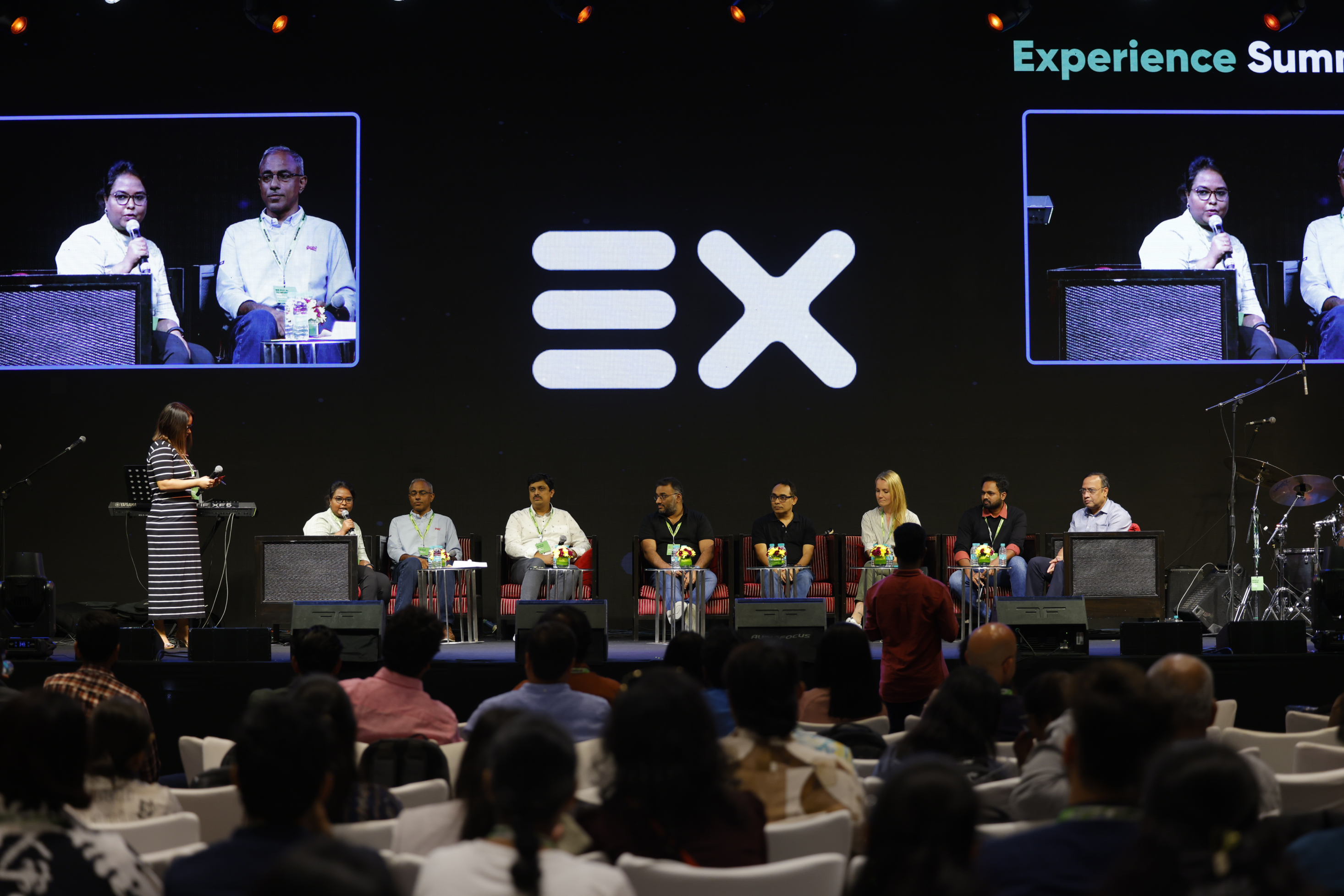 a group of people sitting in chairs in front of a large screen