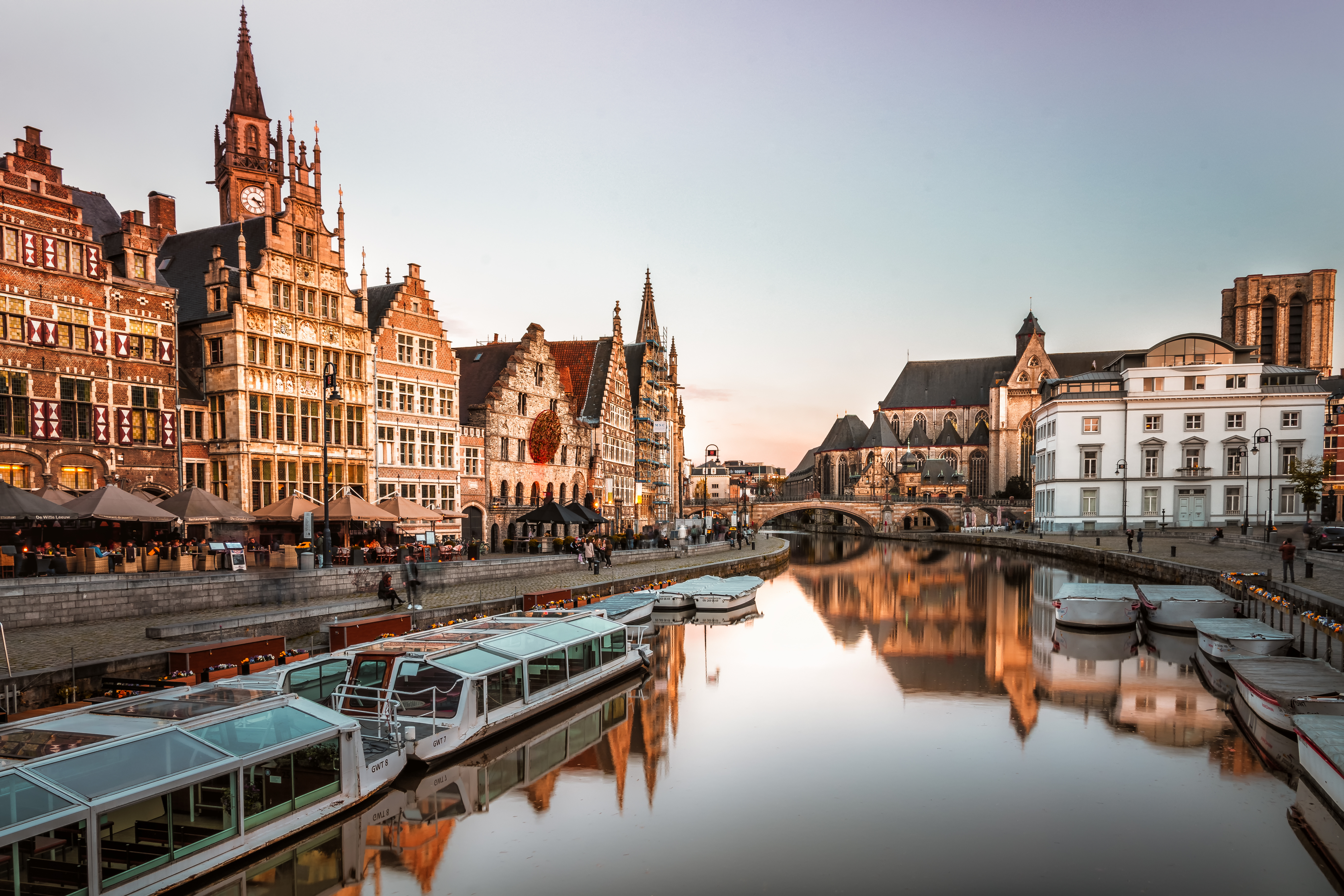 a river with boats on it and buildings in the background with Ghent in the background