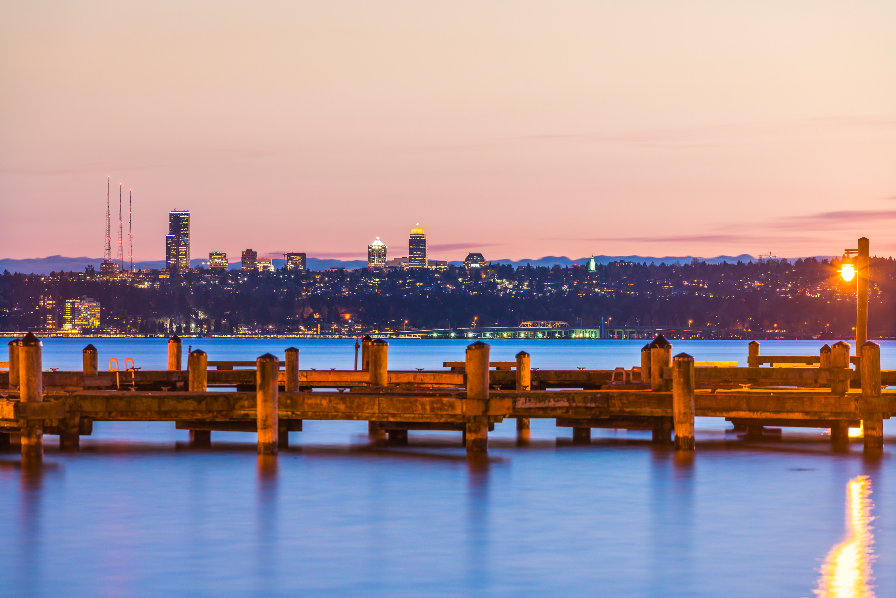 a dock on the water with a city in the background