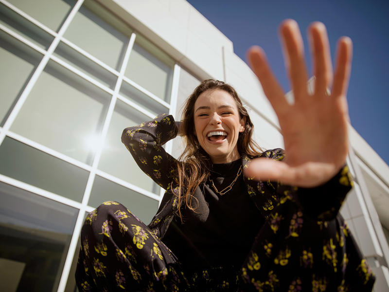 a person smiling and waving her hand