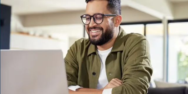 Thumbnail_Trailblazing the way forward with AI agents, a person smiling at a laptop