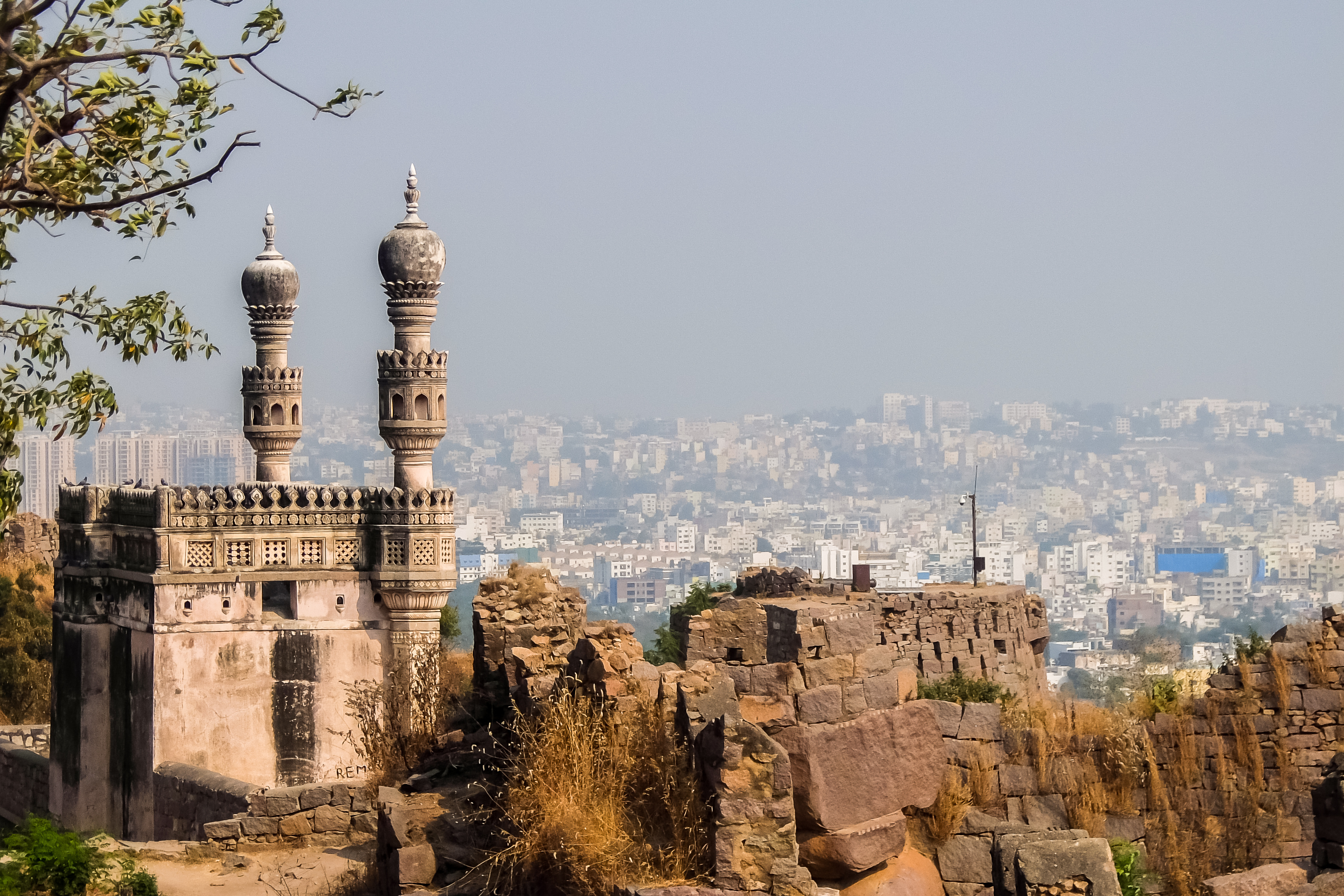 a stone building with towers and a city in the background