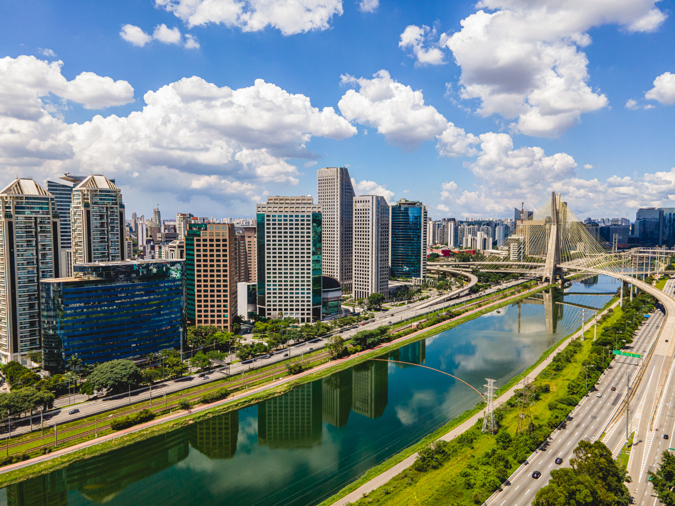 a river with a bridge and a city with buildings and trees