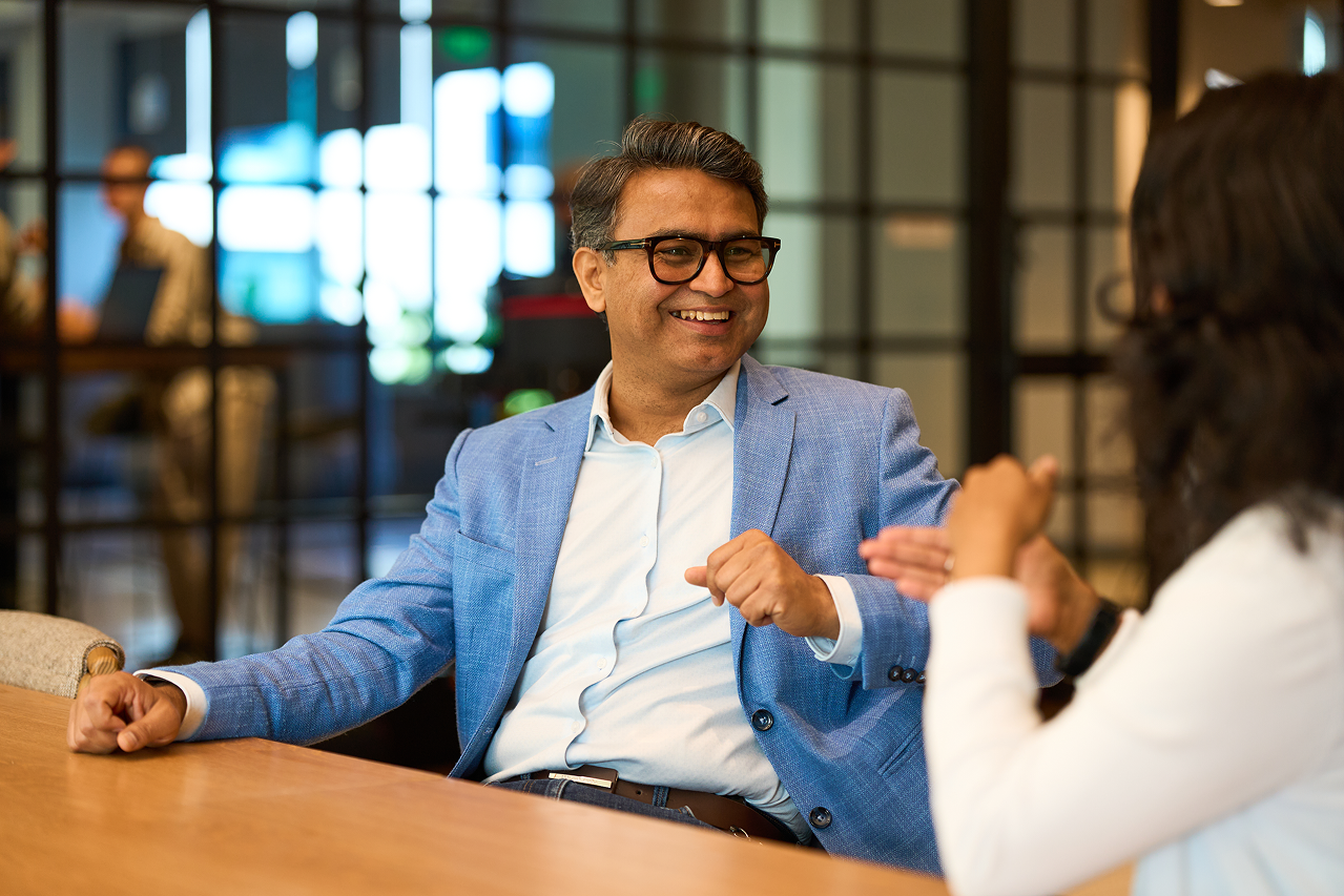 a person in a blue suit sitting at a table with another person in a blue suit